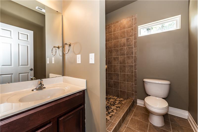 Full bath on first floor of home features large, step-in tiled shower, tile floors.