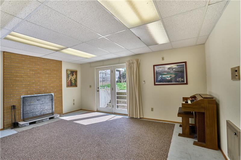 Very Large Downstairs Family Room with Brick Surround Wood Fireplace and French Doors Leading to the Back Yard.