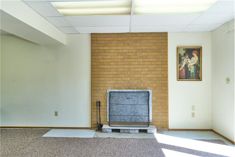 Downstairs Family Room with a Brick Surround Wood Fireplace.