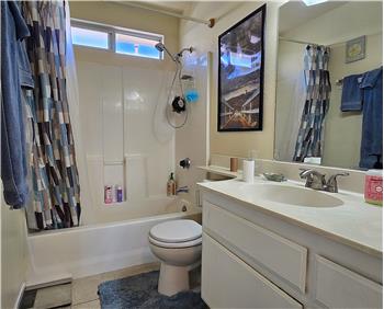 Bright main bath with solidsurface counter, tile floors, and full tub/shower.