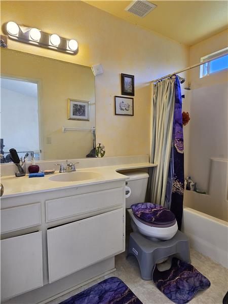 Primary bath with solidsurface counter, tile flooring, and full tub/shower.