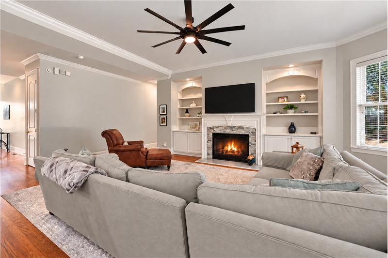 Gas log fireplace with decorative mantel framed by custom built-ins. Great combination of architectural detail, useful storage.