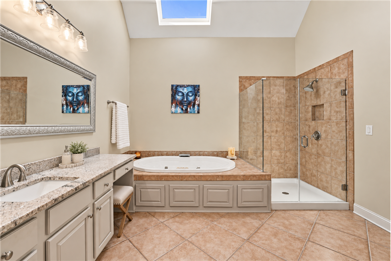 Primary bath made for unwinding. Deep soaking tub, large shower with frameless glass enclosure.