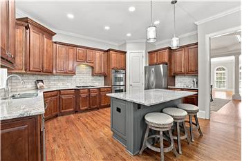 Large island with custom granite counter provides expansive prep area, seating, storage.