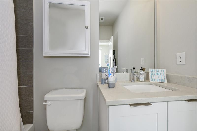 En-suite second bathroom features tub/shower combination with tile surround and tile flooring, vanity with quartz counter.