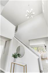 A tall entry ceiling and sculptural chandelier bring light and vertical impact to the stairwell.