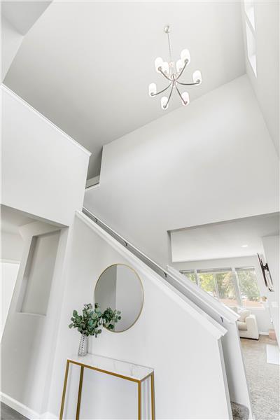 A tall entry ceiling and sculptural chandelier bring light and vertical impact to the stairwell.