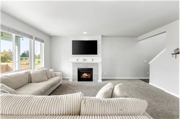 A gas fireplace creates a warm focal point in the living room, while large windows bring in natural light. The TV pictured stays