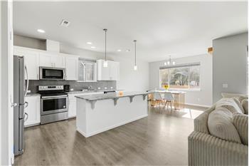 A large kitchen island adds generous prep space and a breakfast bar, with the dining area just steps away.