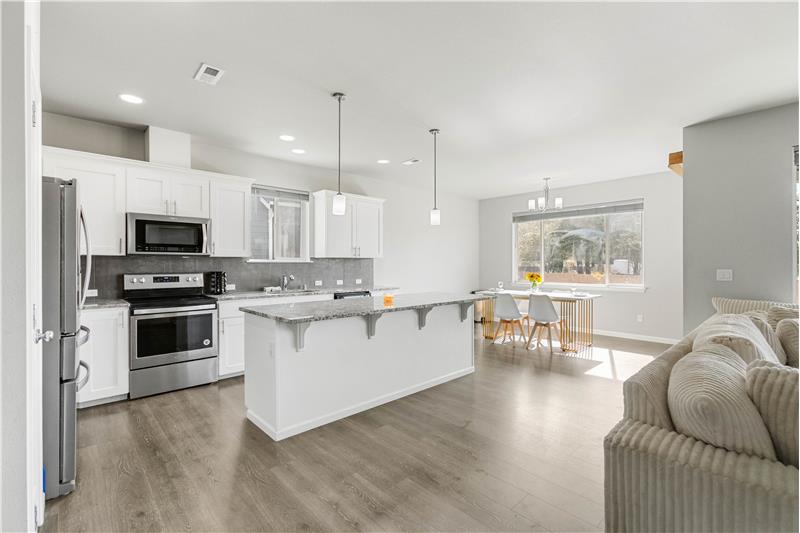 A large kitchen island adds generous prep space and a breakfast bar, with the dining area just steps away.