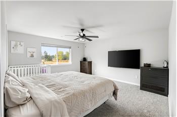 The spacious primary bedroom suite offers a walk-in closet, ceiling fan, and wall-mounted TV that stays with the home.