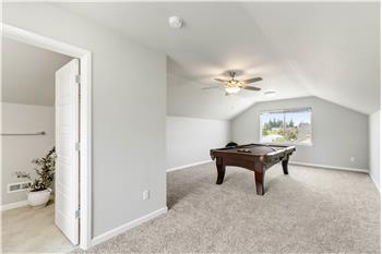 The spacious third-floor bonus room features vaulted ceilings, windows, a ceiling fan, and a convenient three-quarter bath just