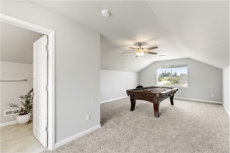 The spacious third-floor bonus room features vaulted ceilings, windows, a ceiling fan, and a convenient three-quarter bath just