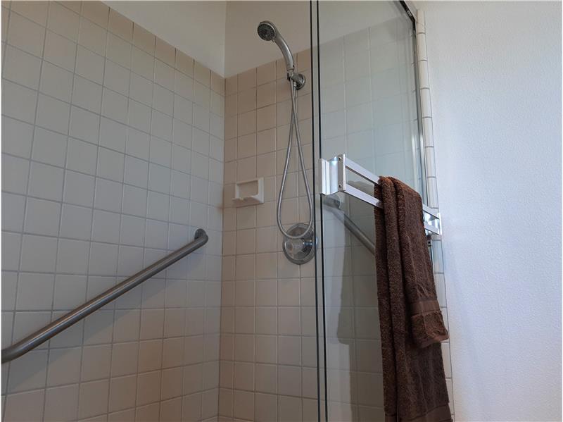 A full-sized shower, complete with grab bar and hand wand, begins the introduction of Bath 1.