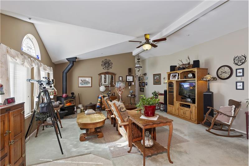 living room with high ceilings, ceiling fan, woodstove