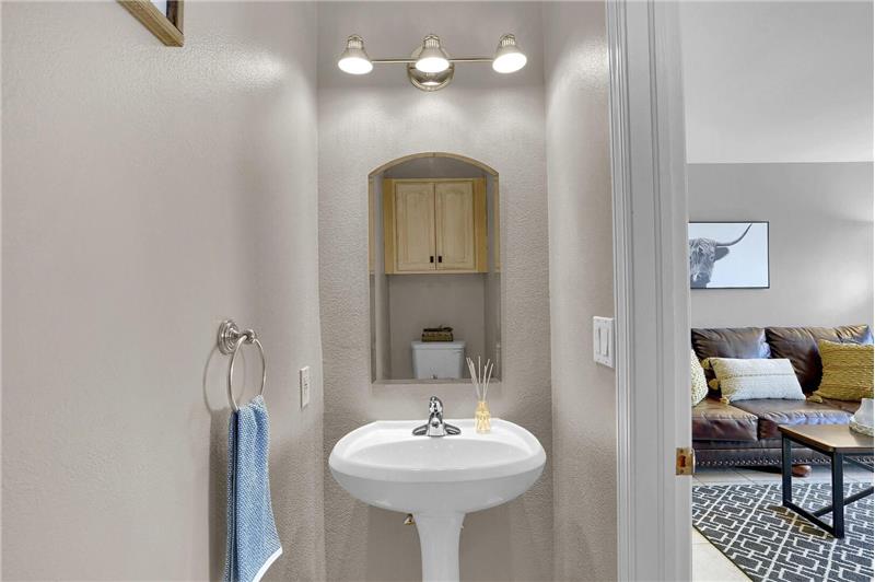 The main-level Powder Bathroom is located off the Living Room and boasts a built-in cabinet and pedestal sink.