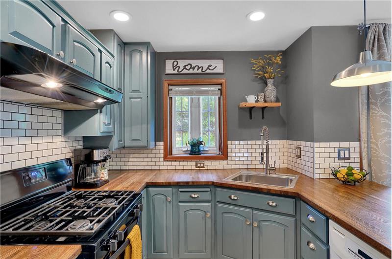 The Kitchen boasts a gas range oven, vent hood, dishwasher, and stainless-steel refrigerator.