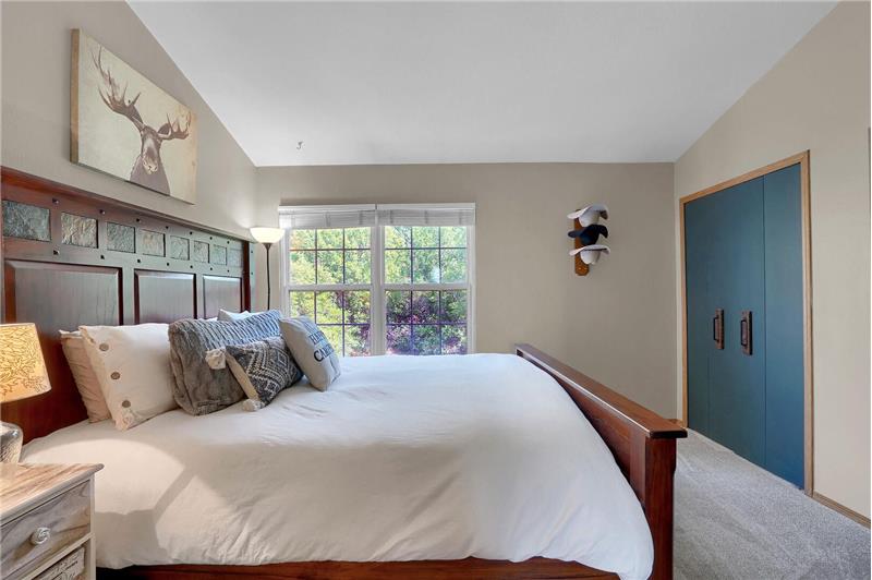 The upper-level vaulted Master Bedroom features neutral tones, window blinds, and double closets.