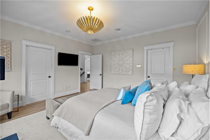 Primary suite features  custom millwork, designer chandelier, walk-in closet, en-suite spa-inspired bathroom, hardwood floors.