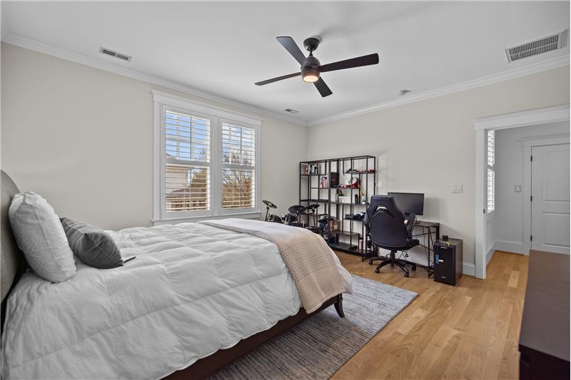 Bedroom features hardwood floors, ceiling fan with light, crown molding, double size closet, plantation shutters.