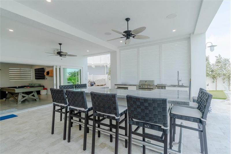 Full outdoor kitchen with gas grill, wet bar, and dining area.