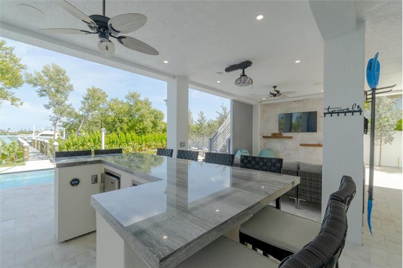 Outdoor kitchen with gas grill, wet bar, and mini refrigerators.