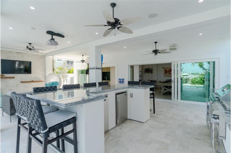 Outdoor kitchen with gas grill, wet bar, and mini refrigerators.