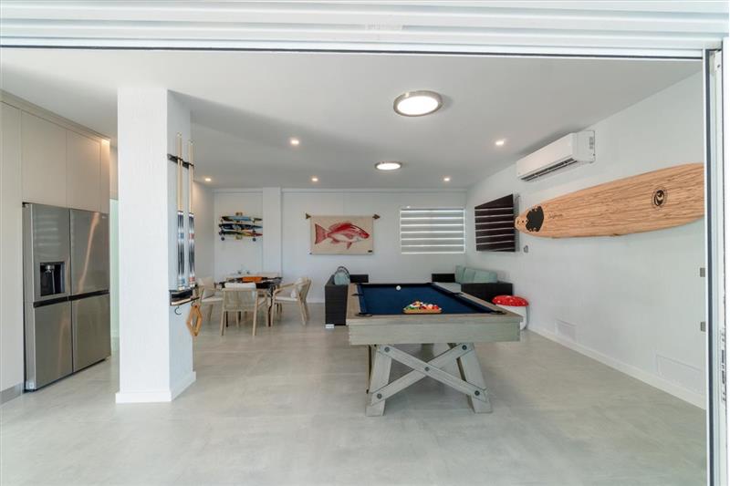 Indoor/outdoor entertainment room with pool table, dominos table, and TV.