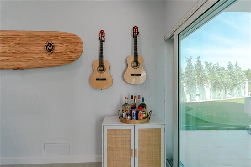 Indoor/outdoor entertainment room with pool table, dominos table, and TV.