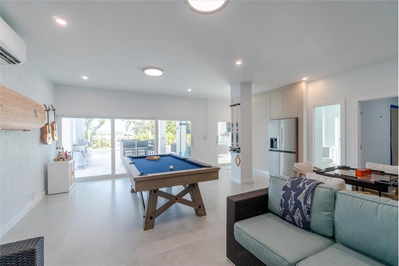 Indoor/outdoor entertainment room with pool table, dominos table, and TV.