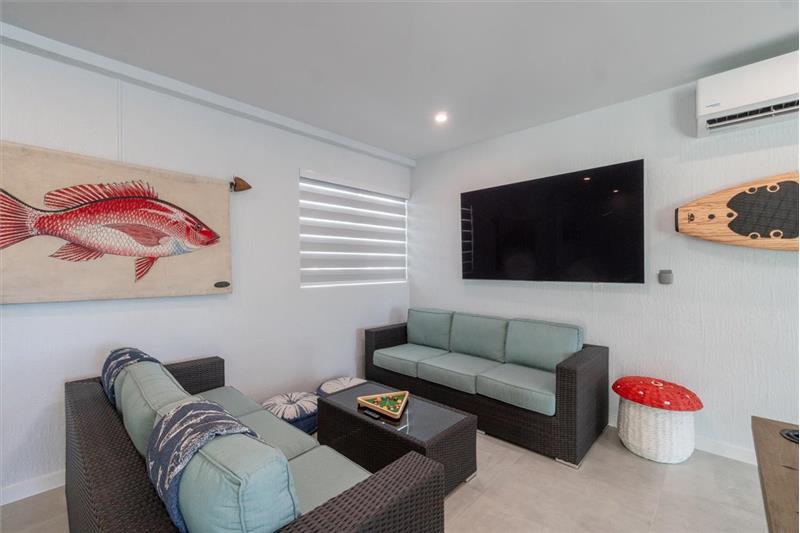 Indoor/outdoor entertainment room with pool table, dominos table, and TV.