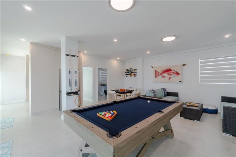 Indoor/outdoor entertainment room with pool table, dominos table, and TV.