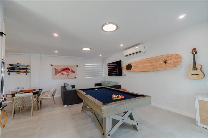 Indoor/outdoor entertainment room with pool table, dominos table, and TV.