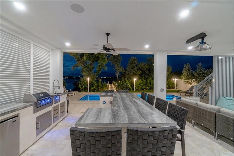 Outdoor kitchen with gas grill, wet bar, and mini refrigerators.