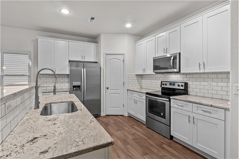 Kitchen features granite counters, LVP flooring, recessed lights, pantry