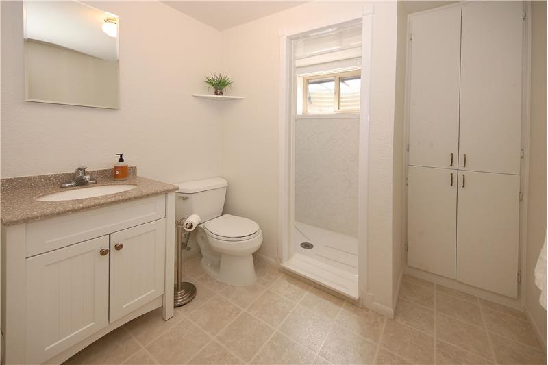 Basement Bathroom with Single Sink Vanity, Linen Closet, and Walk-In Shower