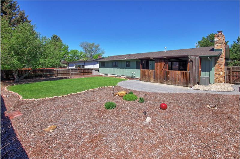 Fenced Backyard with Auto Sprinklers, Garden Beds, and Brick Walkway to the Front of the House