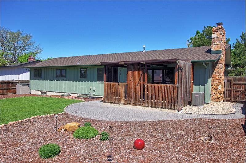 Rear View of Backyard with Grass, Garden Beds, and Brick Walkway to the Front of the House