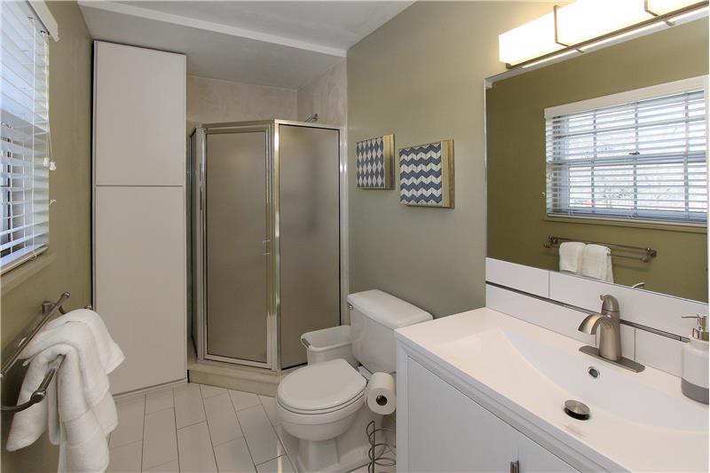Updated 3/4 bath with white subway tile, new vanity, sink, mirror, and lighting.  Cabinet storage!