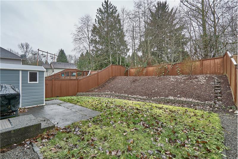 View of the Fully Fenced, Private Backyard with Large Patio and Storage Shed. Greenbelt in back.