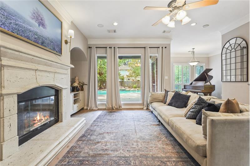 This inviting living room features a cozy fireplace. Natural light floods in through glass doors, offering a view of the backyar