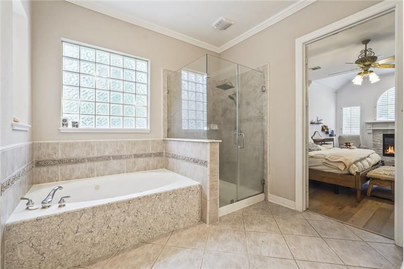 Primary bathroom featuring a soaking tub and frameless shower.