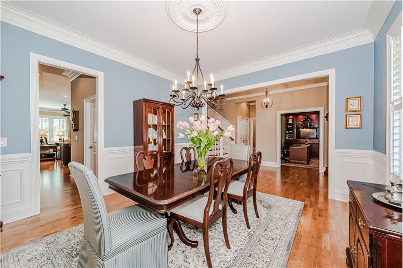 Dining room features beautiful wainscoting, chair rail, crown molding, gleaming hardwood floors, plantation shutters.