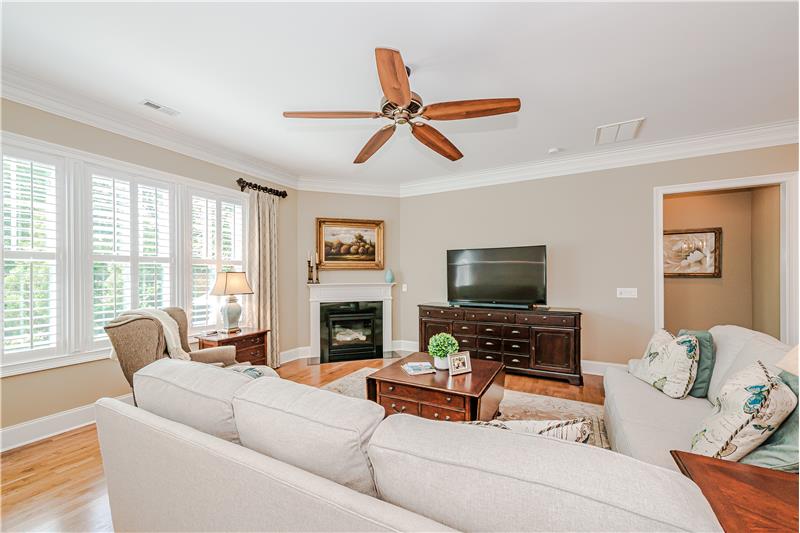 Great room features gas fireplace with decorative mantel, designer ceiling fan. Triple, framed windows.