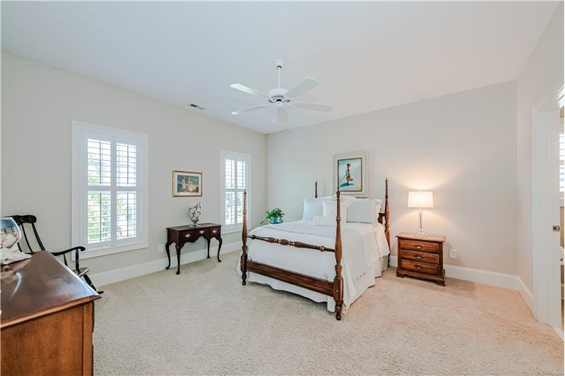 Spacious secondary bedroom features plantation shutters, neutral decor, ceiling fan, walk-in closet.