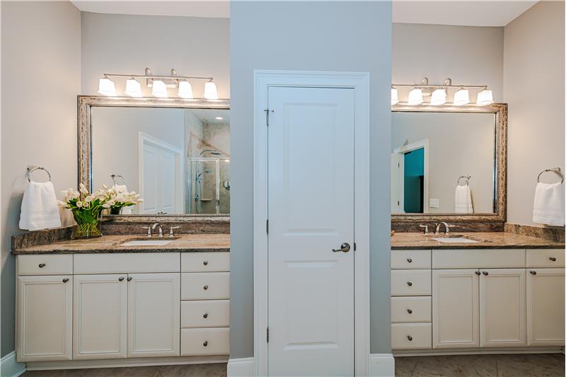 Two large vanities with granite counters, framed mirrors and storage flanking a linen closet. Private WC.