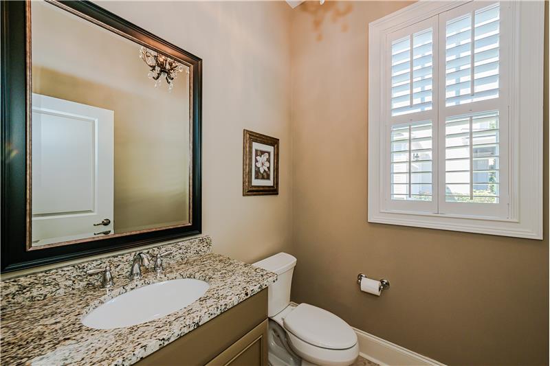 Lovely powder room with custom paint, granite vanity with storage underneath, tile floor, window with plantation shutters.