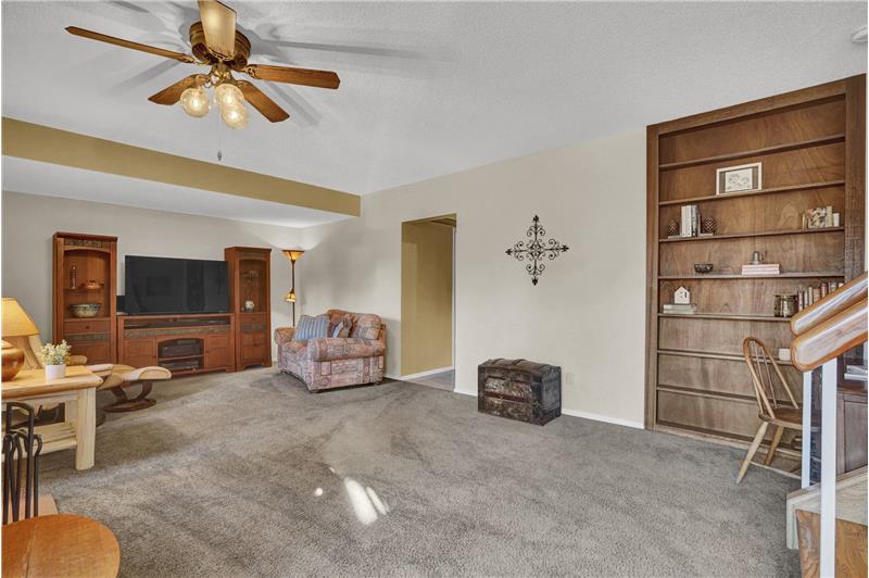 The lower level Dining Room has neutral carpet, a lighted ceiling fan, built-in bookcase, and gas log fireplace