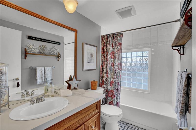 Upper level Hall Bathroom with expanded vanity, framed mirror, and tiled tub/shower