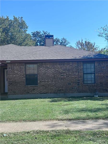 View of front of home featuring a chimney, brick siding, a front yard, and roof with shingles